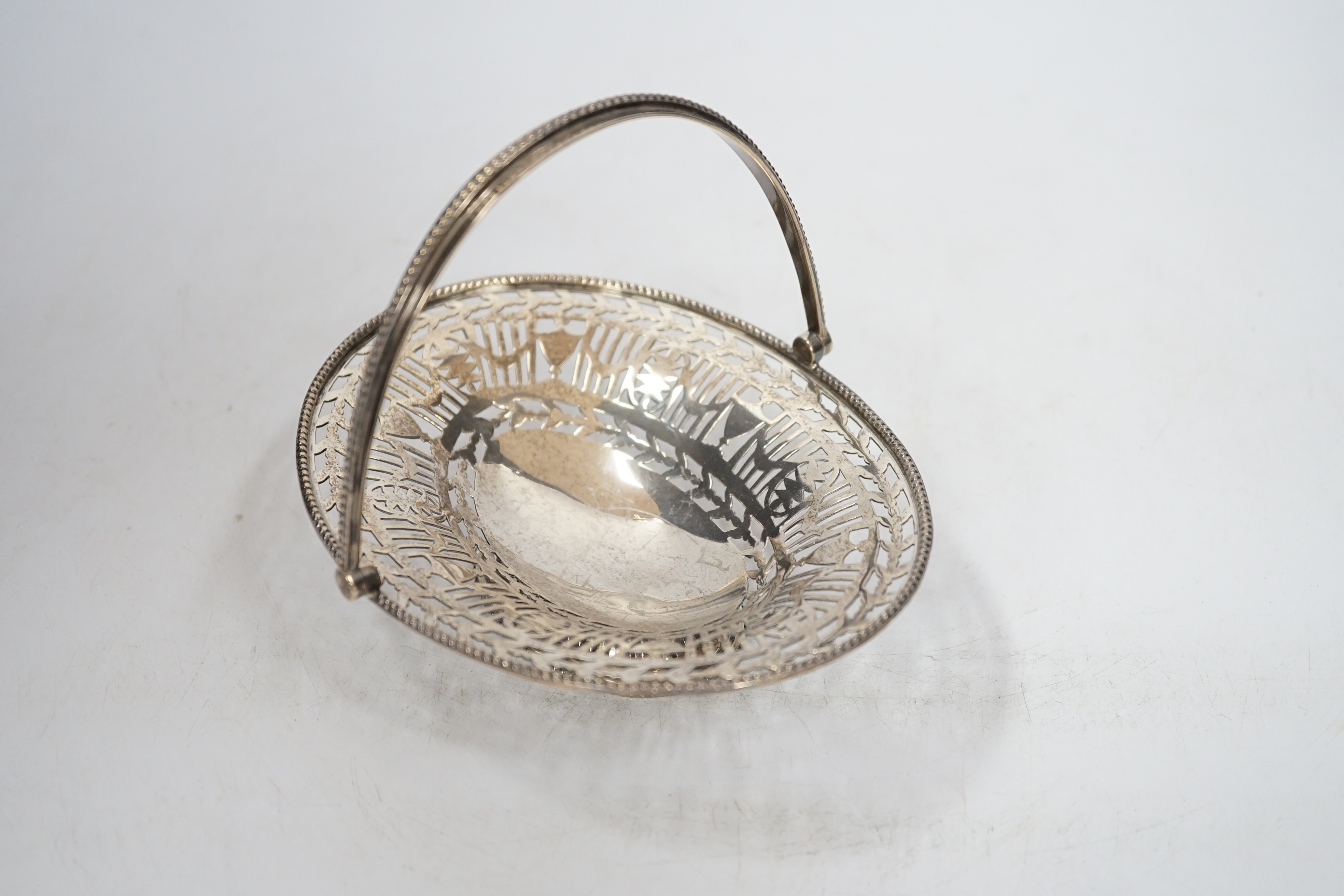 A George V pierced silver oval sweetmeat dish, with swing handle and fretwork decoration, Goldsmiths & Silversmiths Co., London 1912, 16cm, 174 grams